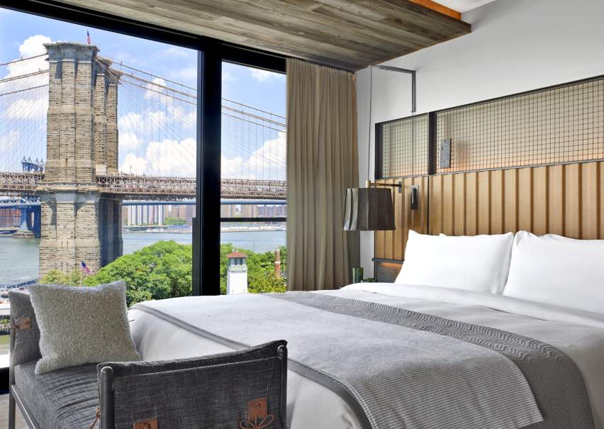 Green plant life decorates a stone wall in the 1H Brooklyn Bridge lobby