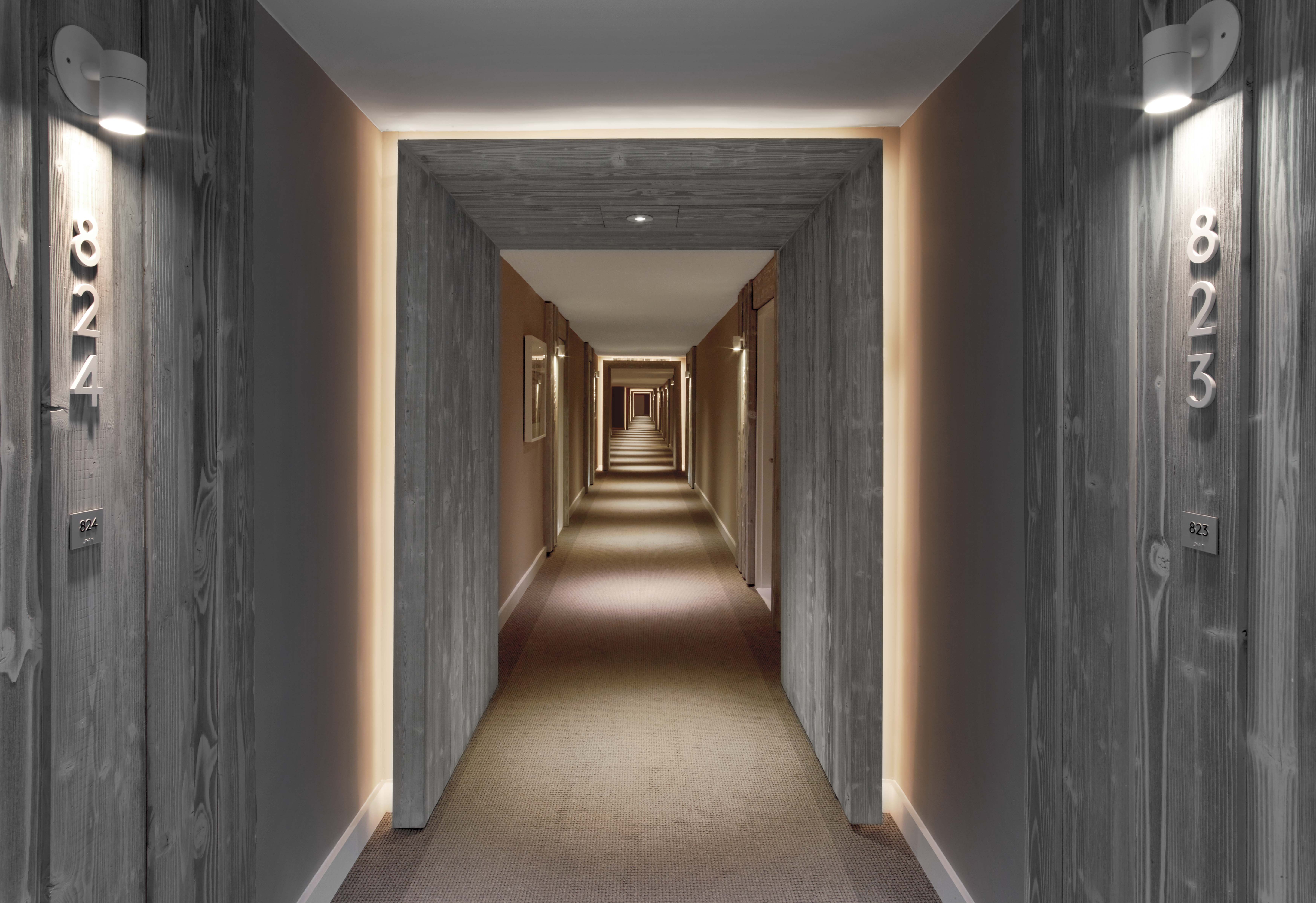 A long hallway of a hotel with wooden doors