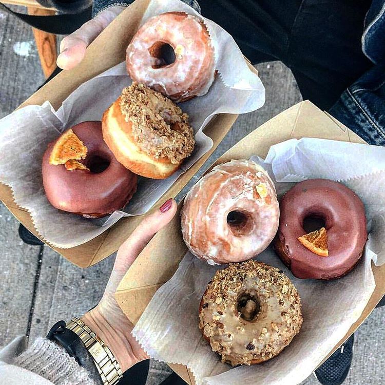 Two containers, each holding three artisinal doughnuts