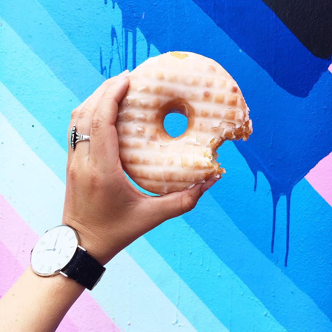 A hand holding a large glazed doughnut