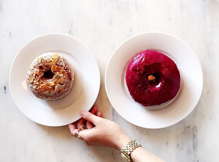 Two different artisinal doughnuts on round white saucers