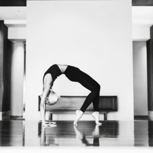 A black and white image of a woman bent in a bridge position