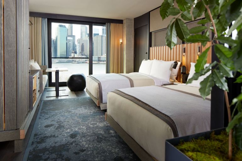 A suite at 1 Hotel Brooklyn Bridge with two beds and a view of Manhattan