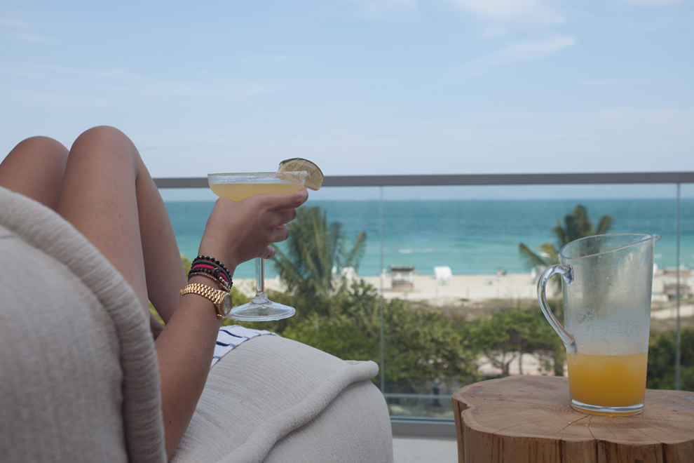 A woman relaxing looking over the beach with a drink in her hand