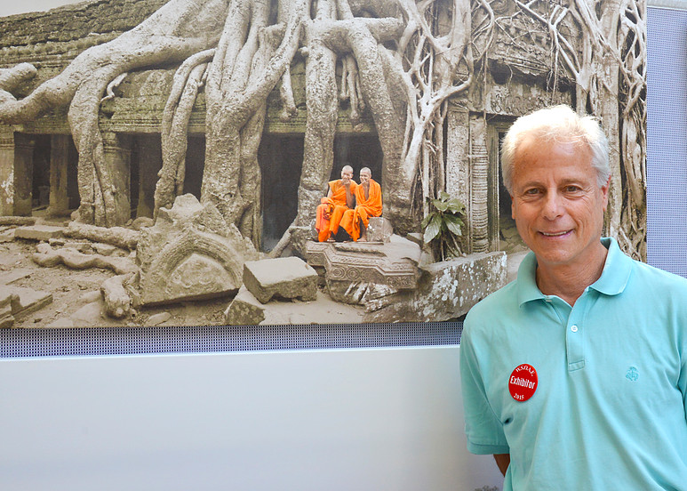 A man standing in front of a photo of monks at a temple