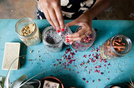 A woman mixing different herbs and spices from jars