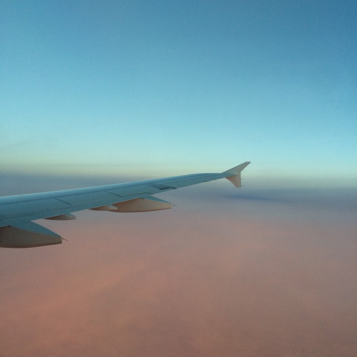 The wing of an airplane in a blue and pink sky