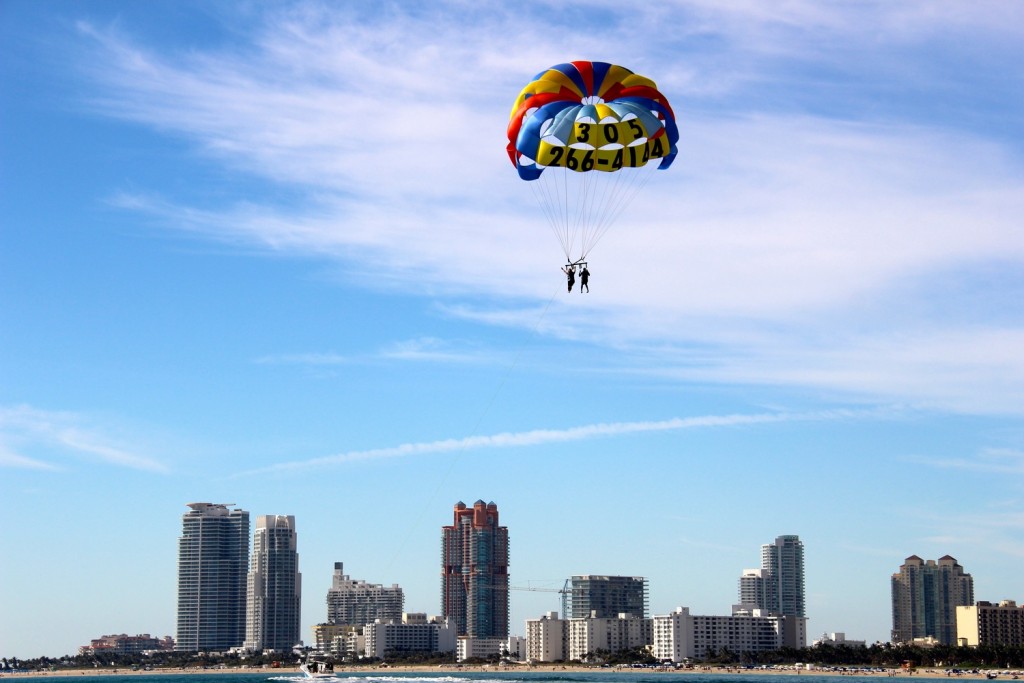 Two people parasailing with the Miami skyline in the background