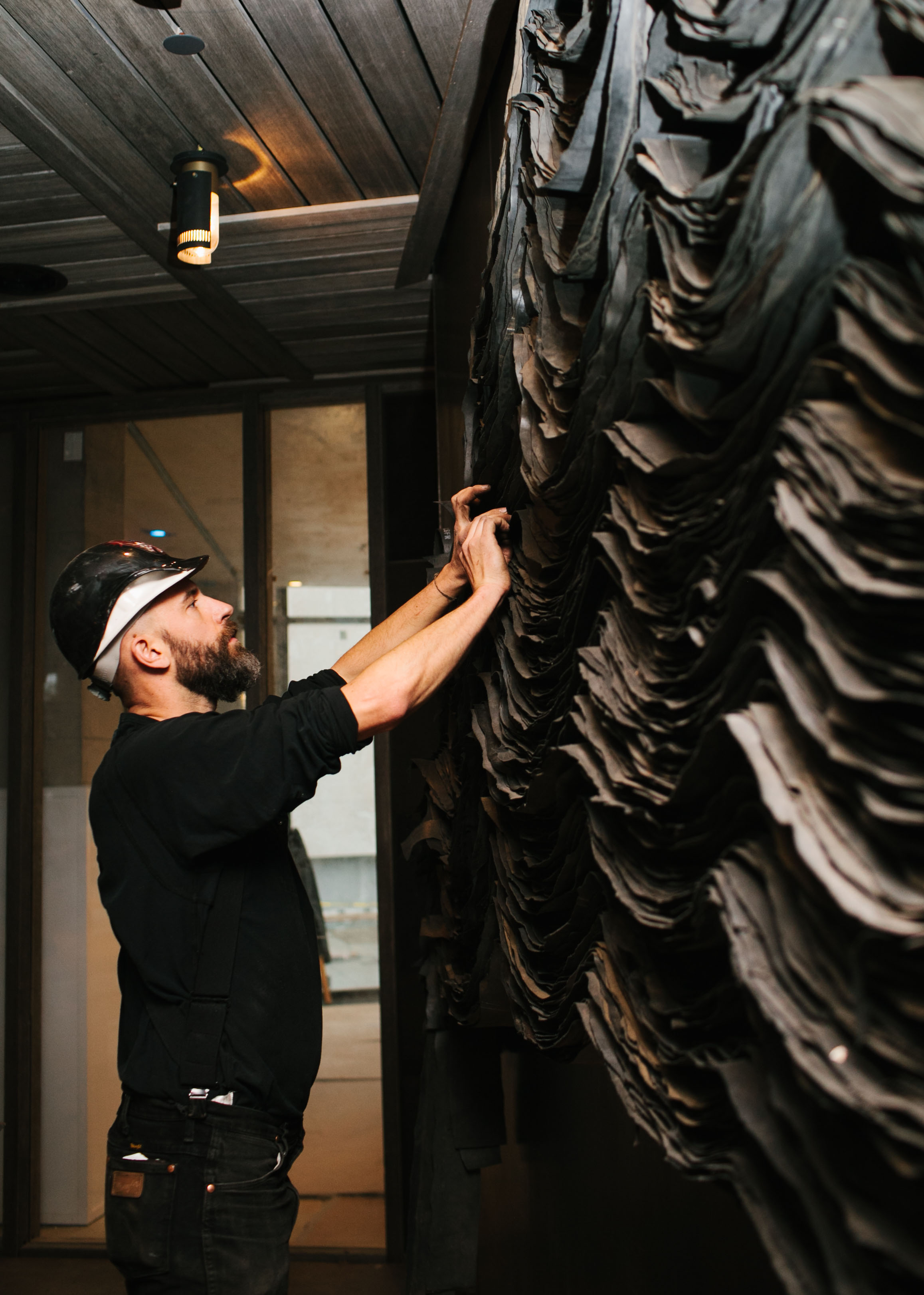 Jarrod Beck installing a decorative wall at 1 Hotel Brooklyn Bridge