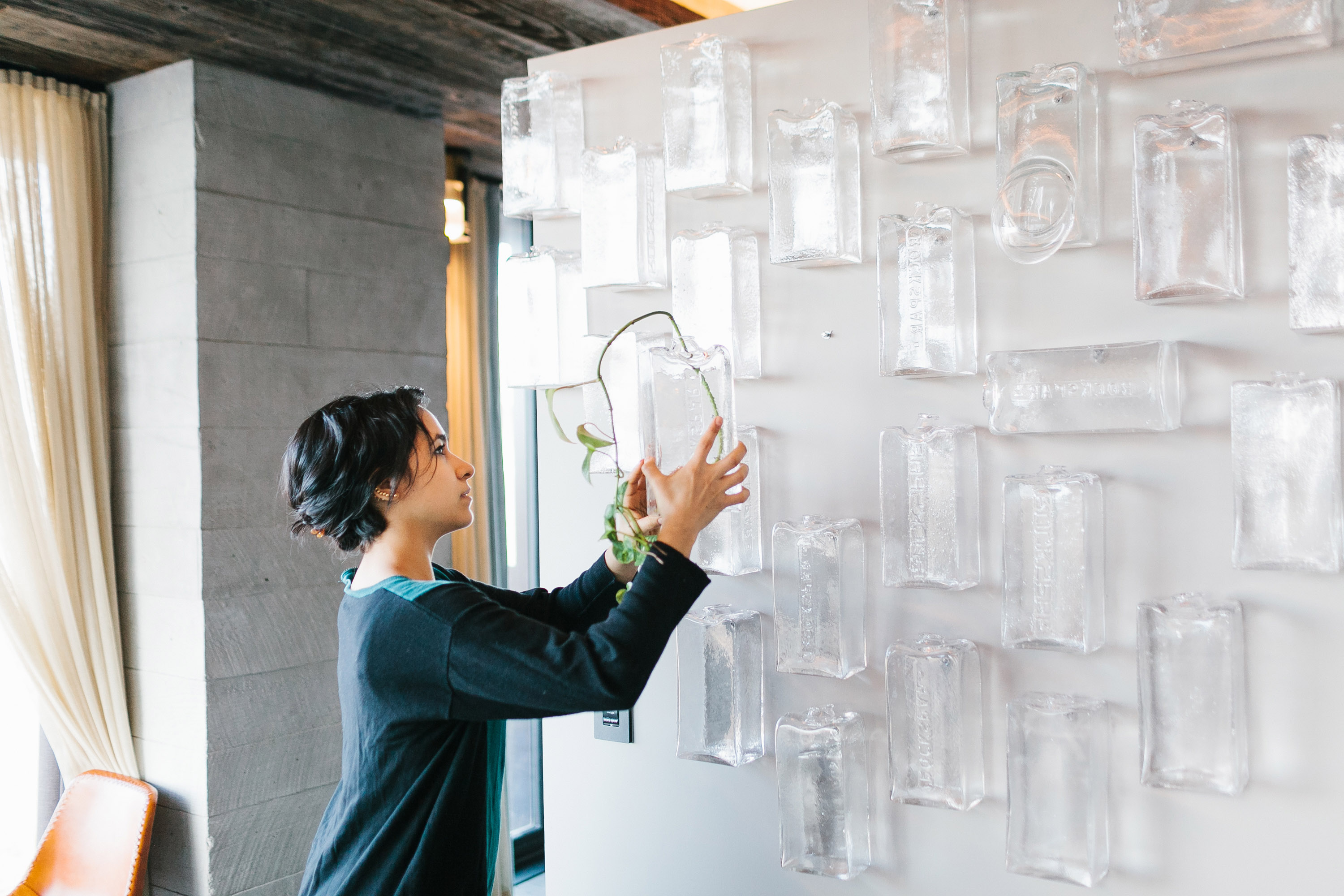 A woman hanging blown glass bricks on the walls of 1 Hotel Brooklyn Bridge