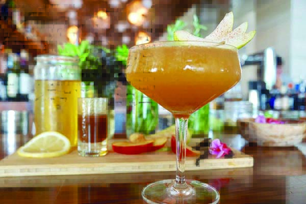A pumpkin colored cocktail in a champagne coupe