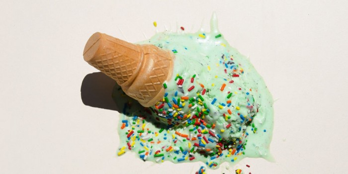 Green ice cream in a cone with sprinkles, smushed into a white surface