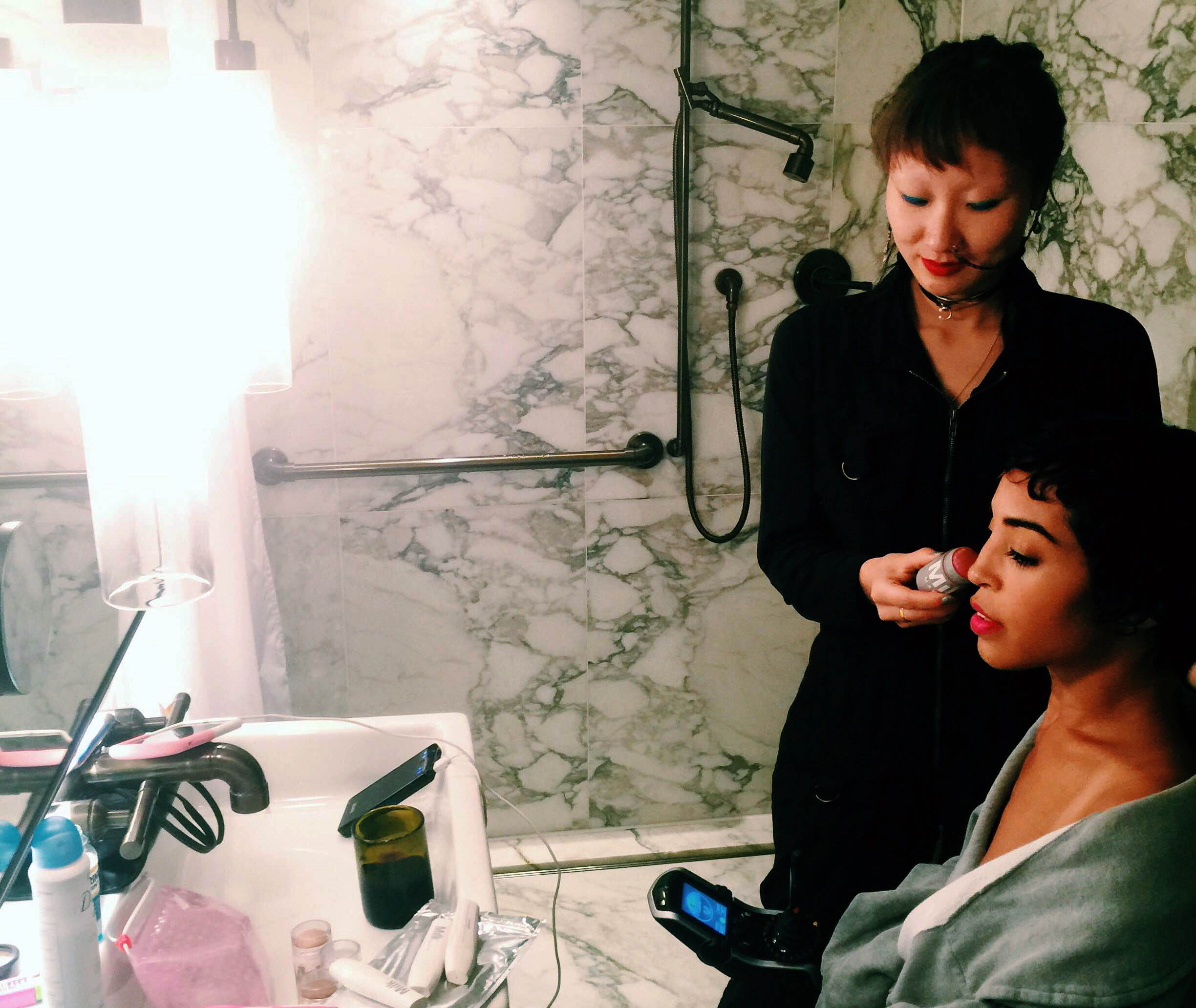 A makeup artist applying blush to a young woman's cheek