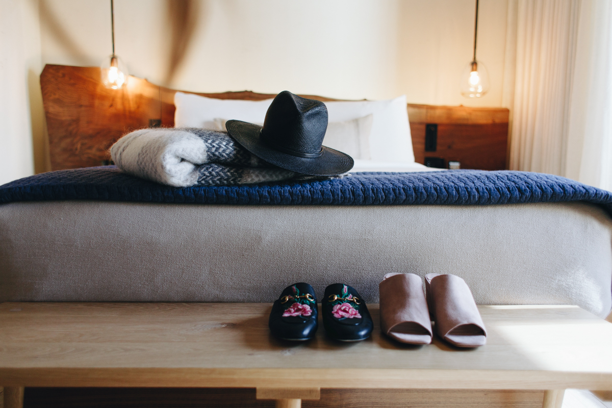 A bed with folded blankets and a hat on it