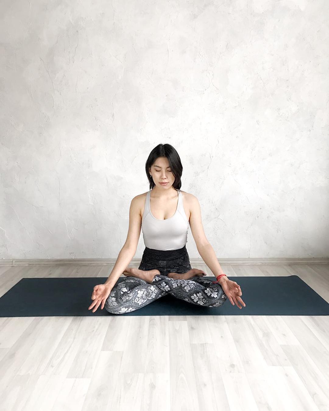 A woman meditating on a yoga mat with crossed legs