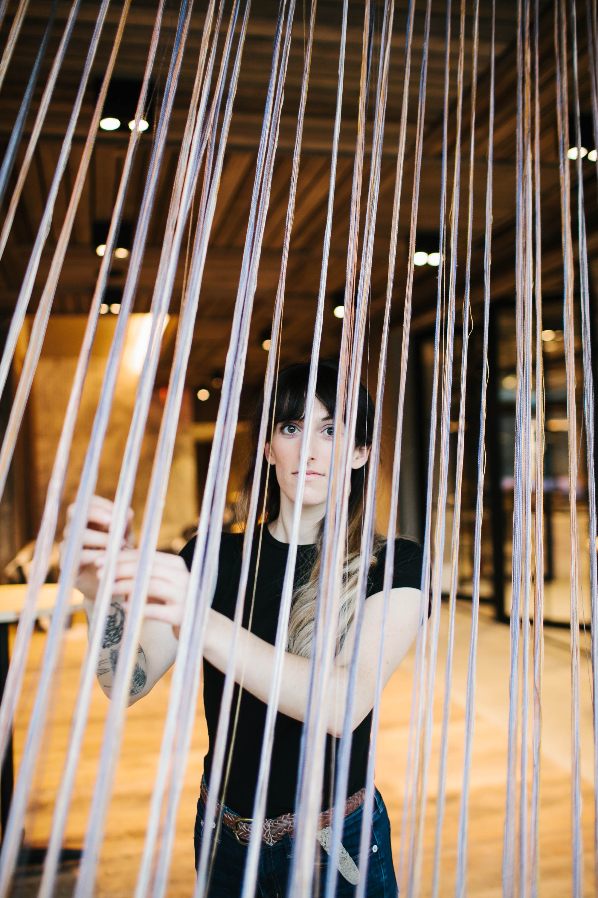 A woman standing behind long colorful strings of fabric