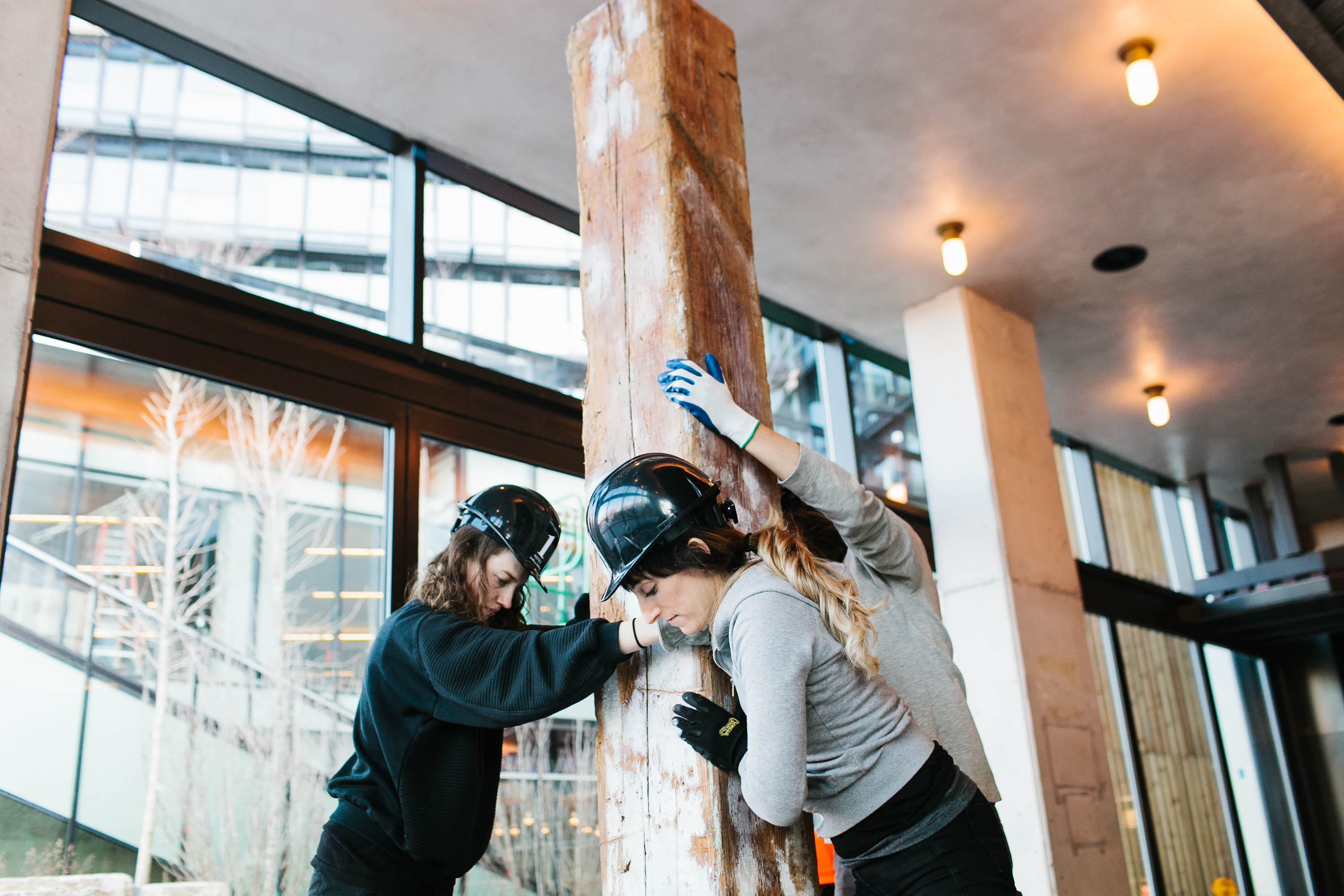 Three women in construction putting a large wooden beam into place