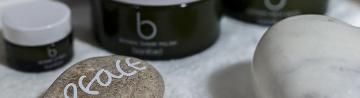 A rock painted with the word "peace" sits next to some spa products