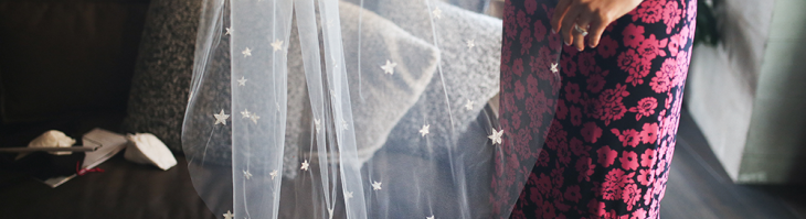 A white translucent wedding veil adorned with stars is held aloft