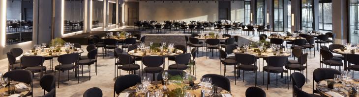 Large event space with round tables and black chairs