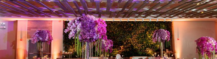 Wedding ballroom with floral arrangements on tables and pink and purple mood lighting