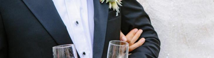 man in tux carrying champagne glasses