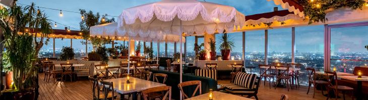 Tables lit up on a rooftop bar overlooking West Hollywood