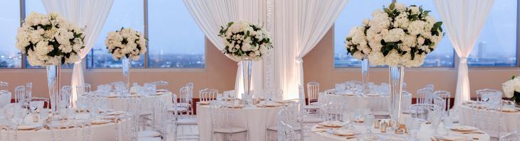 A banquet hall decorated with white linen and flowers