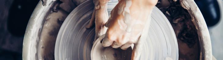Clay covered hands shaping pottery