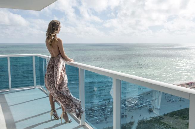 image of a woman standing on a balcony looking over the ocean