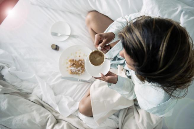 a woman drinking coffee in bed