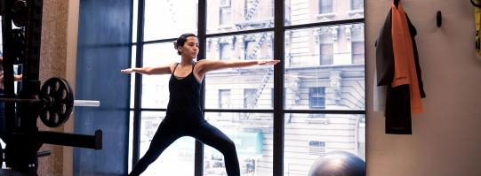woman doing yoga in a gym with floor to ceiling windows