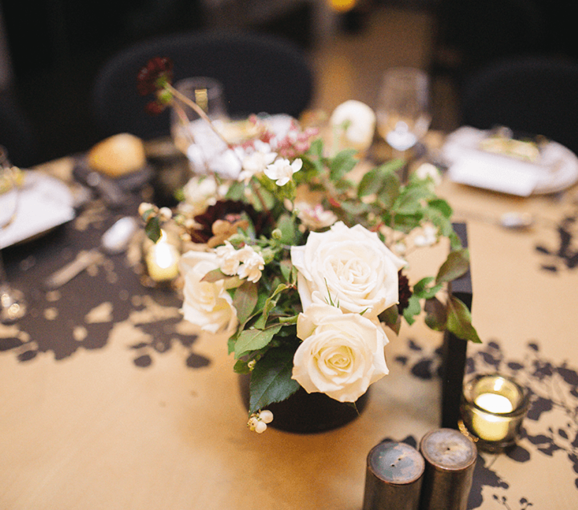 A decorative bouquet of wedding flowers on a round wooden guest table.