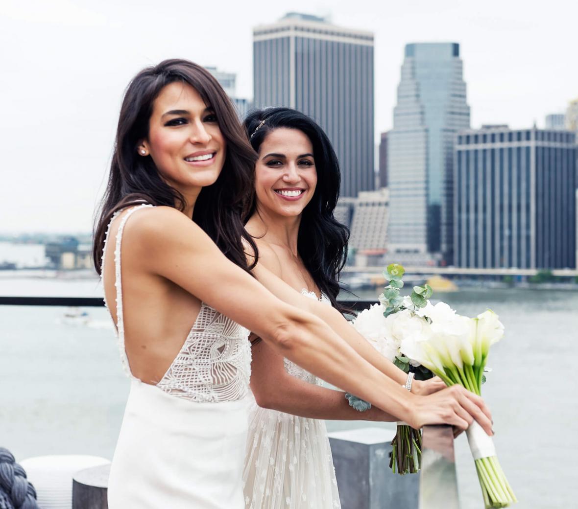 A bride and her maid of honor on a rooftop with a view of Manhattan.
