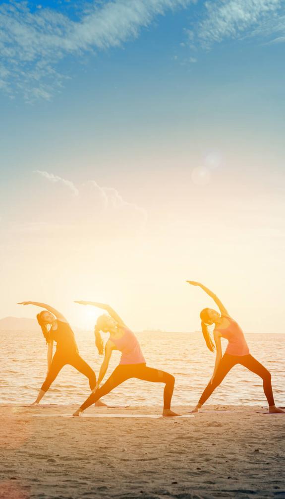 group doing yoga on the beach