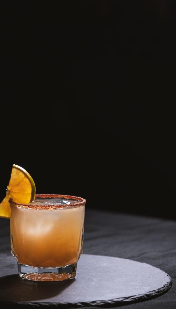 cocktail with orange wedge on rim and ice cubes