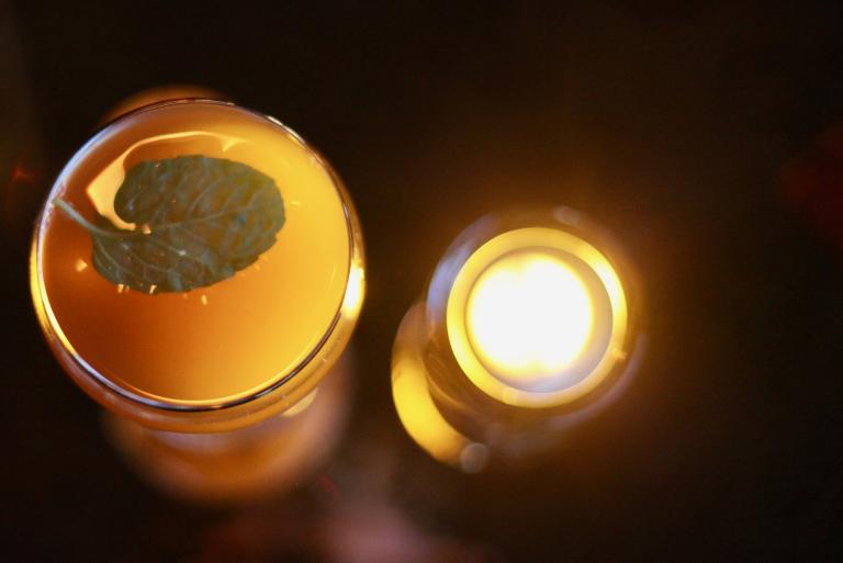 A handcrafted cocktail lit by a nearby candle