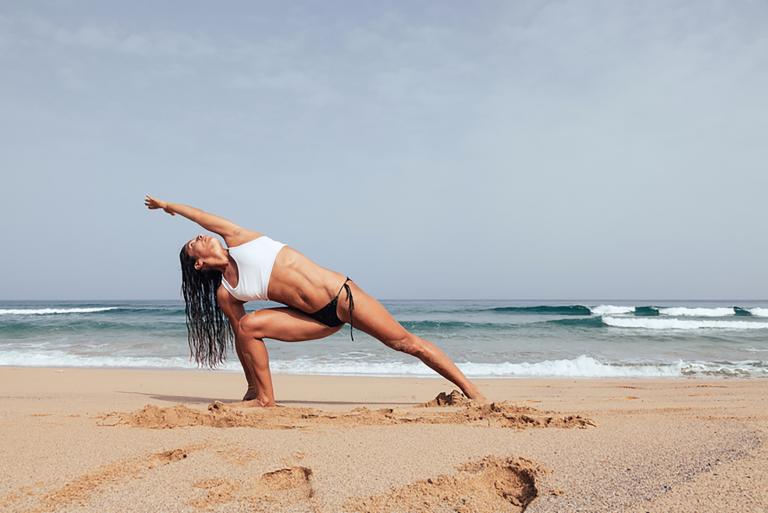 A woman does yoga on a beach